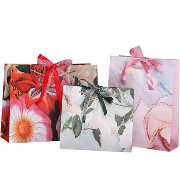 exhiba tres bolsas de papel de regalo coloridas personalizadas con lazo de cinta en diferentes tamaños