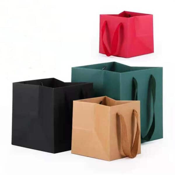 покажите четыре нестандартных квадратных пакета из крафт-бумаги с веревочными ручками разных цветов и размеров