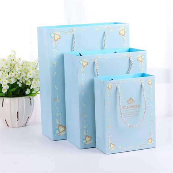 exhiba tres bolsas de papel de regalo laminadas mate personalizadas azules en diferentes tamaños