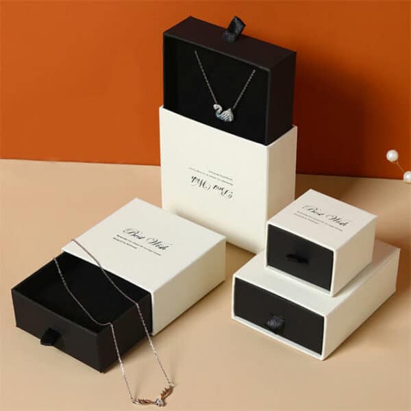 izložite hrpu bijelih i crnih prilagođenih kutija za nakit s otisnutim logotipom u različitim veličinama