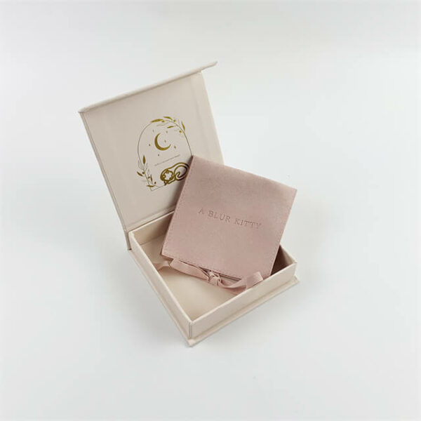 Exhiba una caja de embalaje de joyería magnética personalizada con tapa abatible de color crema con una bolsa de joyería de microfibra rosa en el interior