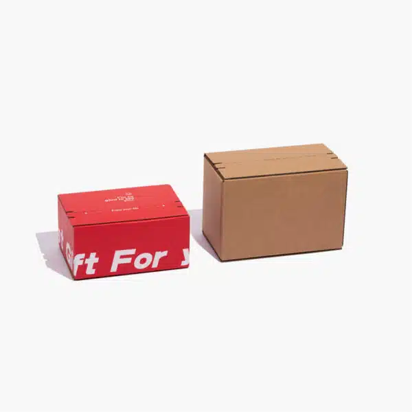 กล่องกระดาษสำหรับจัดส่งแบบกำหนดเองสองกล่องที่มีกาววางเคียงข้างกัน กล่องหนึ่งเป็นกระดาษคราฟท์และอีกกล่องเป็นกระดาษพิมพ์