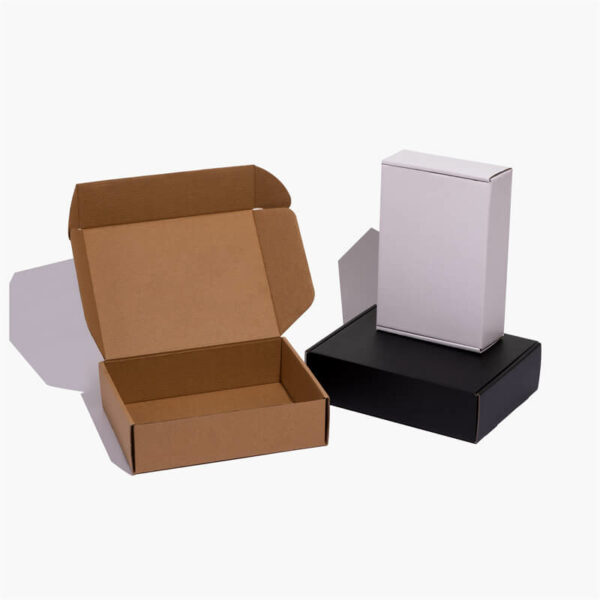 три прилагодени стандардни поштенски кутии се уметнички поставени во различни пози, една е бела, една е крафт, една е црна