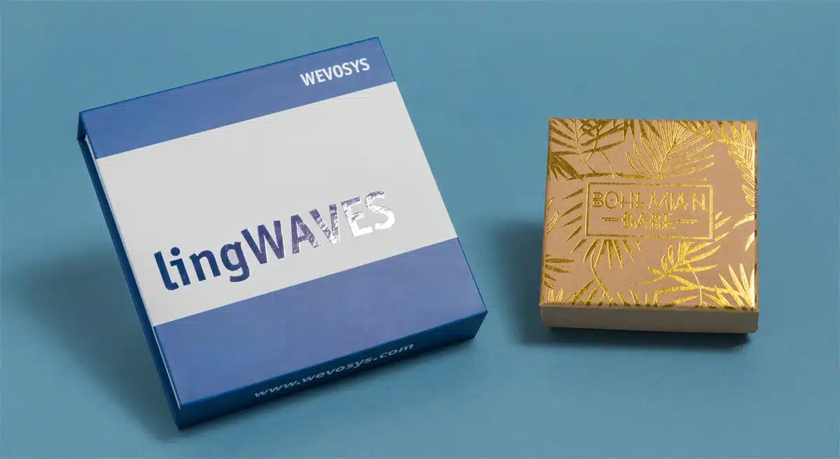 აჩვენეთ ორი მორგებული ბრენდის ყუთი ლურჯ ფონზე, რომლებიც ცალ-ცალკე აჩვენებს ადგილზე UV ლოგოს და ცხელი ფოლგის ლოგოს