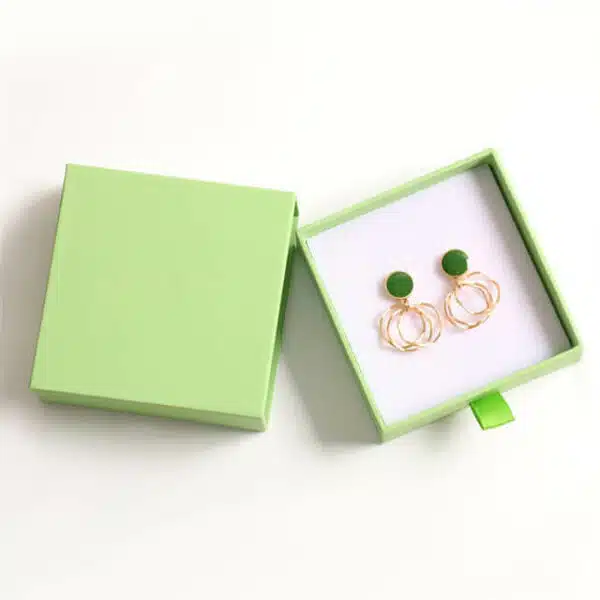 parodyti žalią tinkintą kartoninę auskarų stalčių dėžutę su pora auskarų viduje