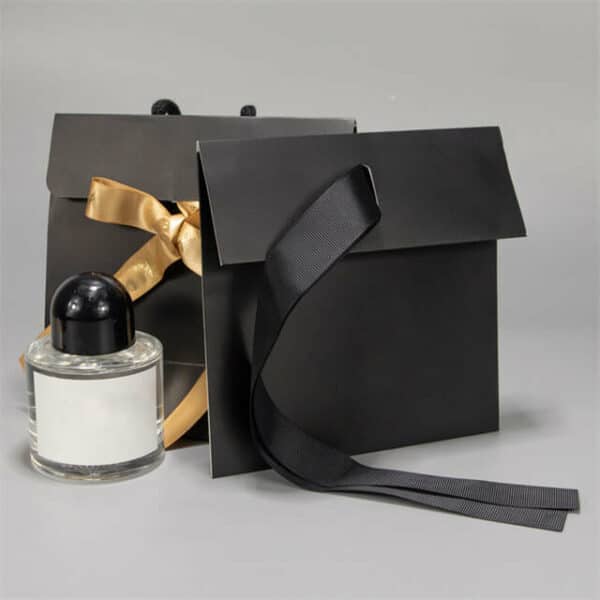 eksponuojami du juodi nestandartiniai dovanų popieriniai maišeliai su atvartu, vienas iš jų yra išlankstytas.