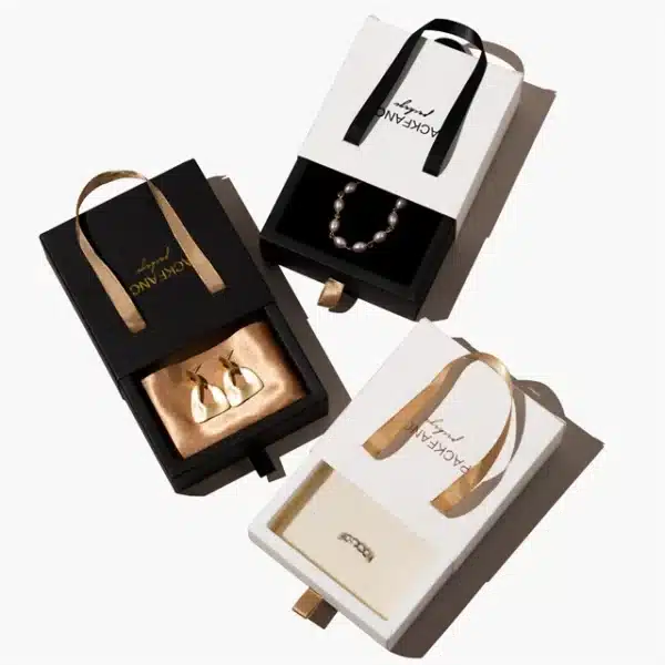 Élégantes boîtes à bijoux avec tiroir en carton personnalisé noir et blanc avec poignée, affichant des bijoux.