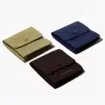 სამი მორგებული სამკაულის ჩანთა სხვადასხვა ფერში, ლამაზად მოწყობილი თეთრ ფონზე. თითოეულ ჩანთას აქვს მომრგვალებული სახურავი ცენტრალური ღილაკით.