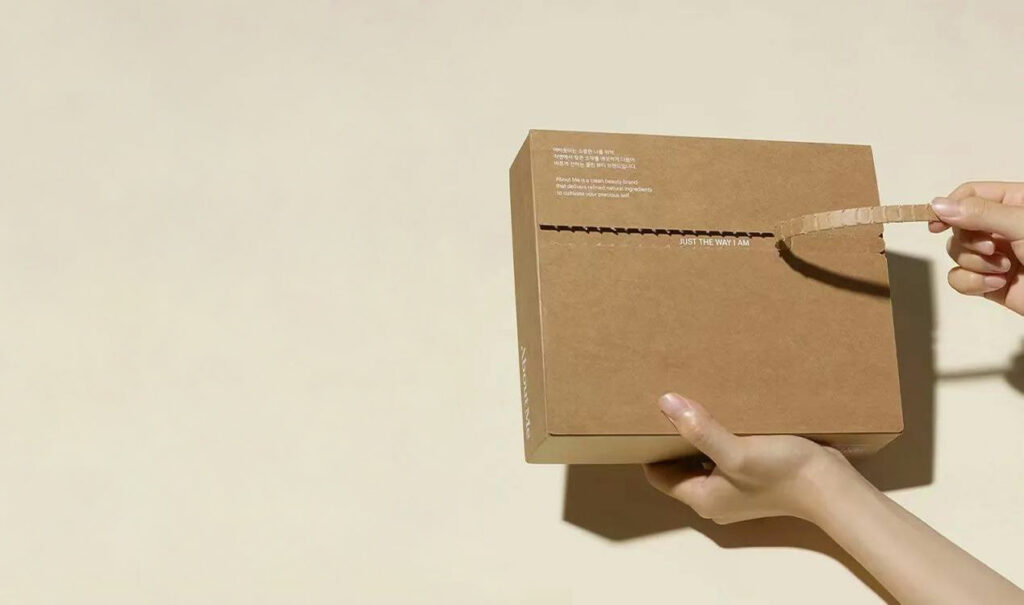 пар раце држат една лесно отворена крафт кутија за пошта и покажуваат како да ја отворите