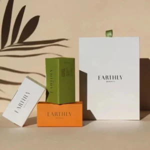 Stylishly arranged luxury soap packaging boxes in white, green, and orange with the brand name printed, casting elegant shadows on a beige background.