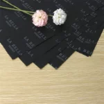 რამდენიმე ფურცელი შავი ქსოვილის ქაღალდი მოათავსეთ ხის მაგიდაზე და მათზე ორი ყვავილი