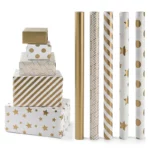 სასაჩუქრე ყუთების კოლექცია შეფუთული ქსოვილის შესაფუთი ქაღალდით სხვადასხვა ოქროსა და თეთრი ნიმუშებით, მათ შორის ზოლებით, წერტილებითა და ვარსკვლავებით.