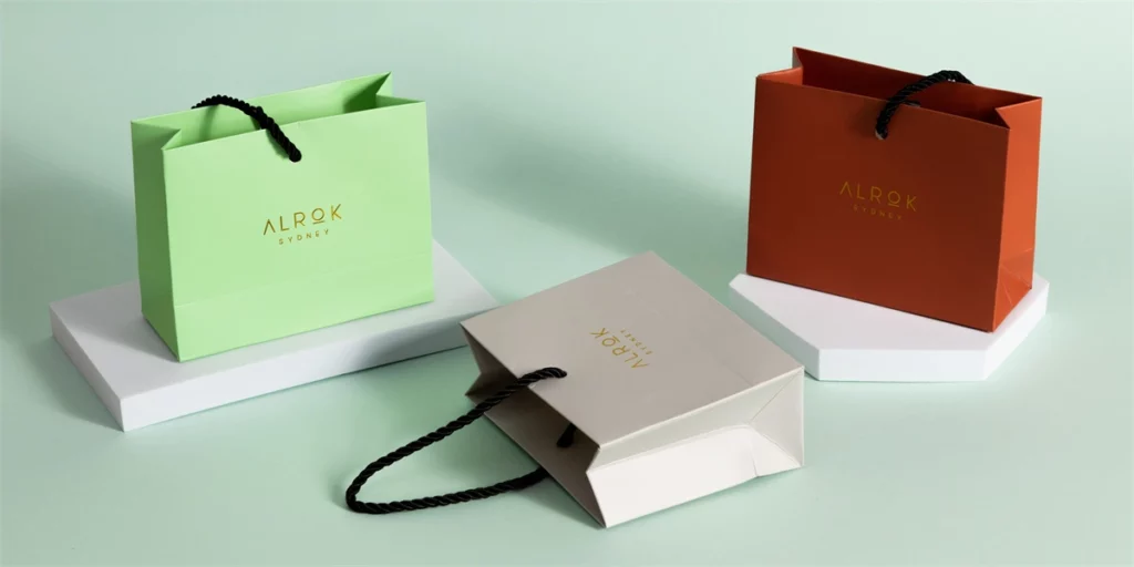 Hot Foil Stamping VS Spot UV - ყველაფერი, რაც გსურთ იცოდეთ 6 აჩვენეთ სამი მორგებული ქაღალდის ჩანთა ოქროს ფოლგის ლოგოთი ერთ ზედაპირულ ფონზე