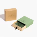 ერთი დახურული კრაფტის უჯრის ყუთი დგას მწვანე ღია უჯრის გვერდით