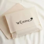 აჩვენეთ ორი მორგებული ბამბის ტილოს კონვერტის მტვრის ჩანთა, და ერთ ჩანთას დახურულ მდგომარეობაში აქვს პატარა საჩუქარი შიგნით