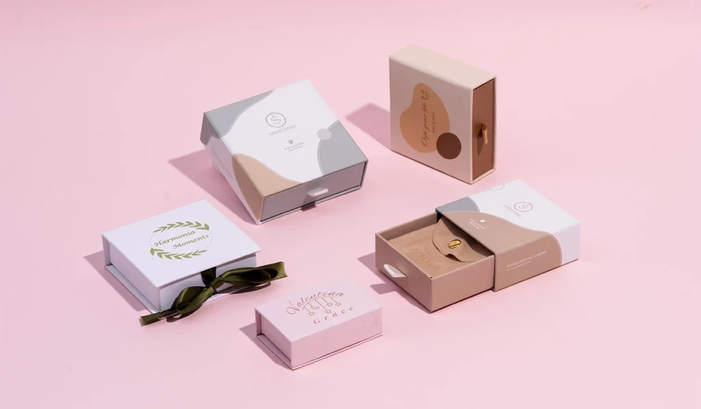 Stilvolle und umweltfreundliche Schmuckverpackungsboxen in neutralen Tönen auf rosa Hintergrund.