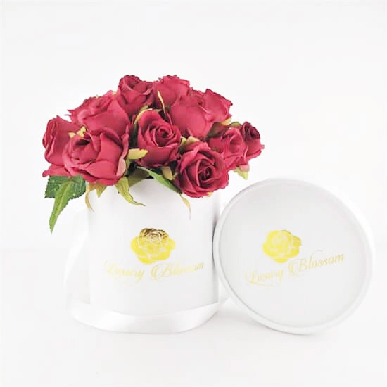 eine weiße maßgeschneiderte Blumenröhre mit einem Strauß roter Rosen darin